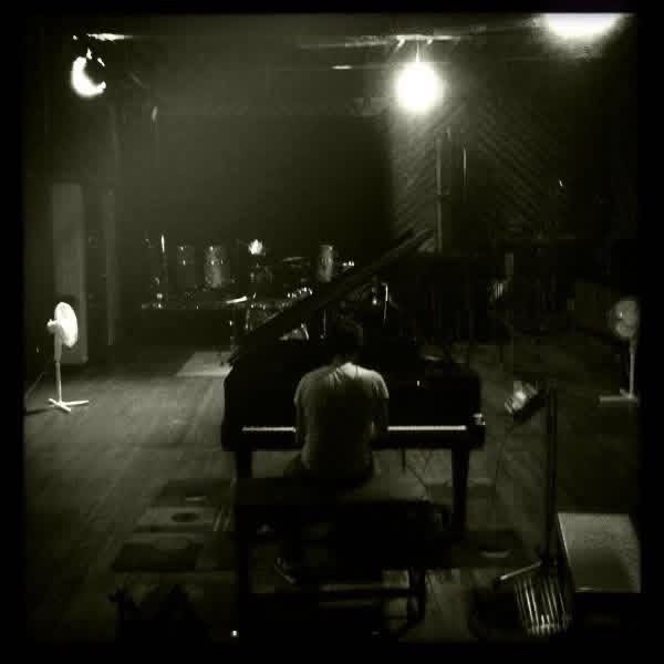 Chris LoPresto alone at a grand piano in a dark rehearsal room
